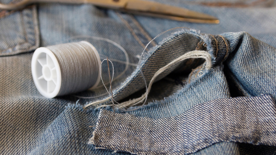 Sewing needles and thread, embroidered on the denim pants. Repair of defects Sewing needles and thread, embroidered on the denim pants. Repair of defects